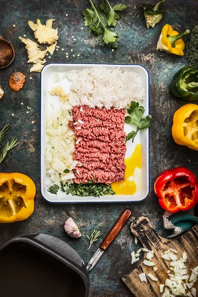Meat stuffing preparation with ground meat, rice, chopped onion, egg , garlic and fresh green seasoning for stuffed paprika peppers , dark rustic background, top view