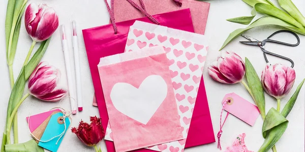春天的工作空间 带有郁金香花 粉色纸袋和有心的信封 顶部视图 复制空间 母亲节礼物和贺卡 — 图库照片