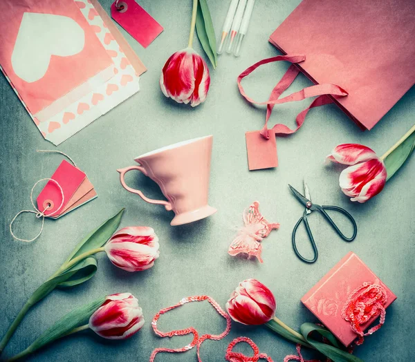 静谧的生活与郁金香 粉红色的杯子 购物袋 礼品盒 剪切面和纸信封与心脏 顶视图 平铺风格 母亲节问候概念 — 图库照片