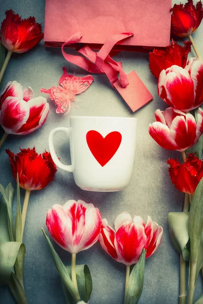 赤いハートのマグカップ 新鮮なチューリップの花やショッピングバッグ トップビュー 抽象的な愛と挨拶の概念 — ストック写真