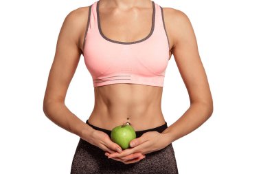 Bir kadın elinde yeşil, sulu bir elmayı karnının arka planına doğru tutuyor, Preza, bir meyve var. Vejetaryenlik, diyet, vücut bakımı. İnce, gergin bir figür. Beyaz arkaplan, izole et.