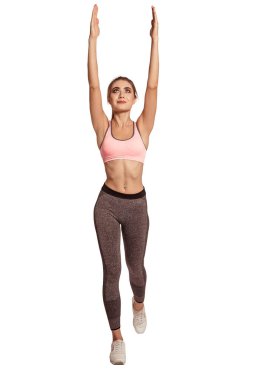 Spor giysili bir kadın beyaz izole bir arka planda Tanrı 'nın duruşunda duruyor. Eller yukarı, esneyin, esneyin, ısının. Sıkışmış vücut. Dengeyi koru.