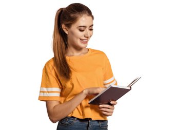 Sarı tişörtlü güzel bir kız öğrenci, elinde kitap tutuyor ve okuyor. Eğitim al, üniversitedeki derslere hazırlan, enstitüye git. Genç mezun. Beyaz arka plan, tecrit. Boşluğu kopyala.
