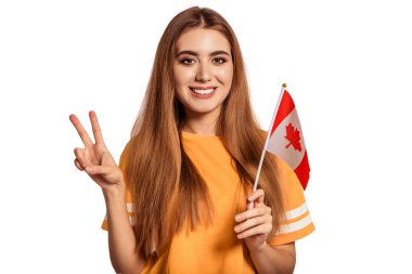 Güzel genç bir kadın elinde Kanada bayrağını tutuyor ve Victoria, Peace, Pacif işaretini gösteriyor. Değişim öğrencisi yabancı bir dil öğreniyor. Turist seyahati. Beyaz arka plan. İzole et