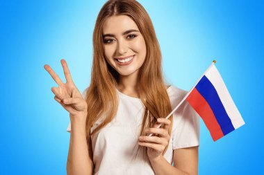 Güzel bir genç kadın elinde Rusya bayrağını tutuyor ve Victoria, Peace, Pacif işaretini gösteriyor. Değişim öğrencisi yabancı bir dil öğreniyor. Seyahat eden turist.