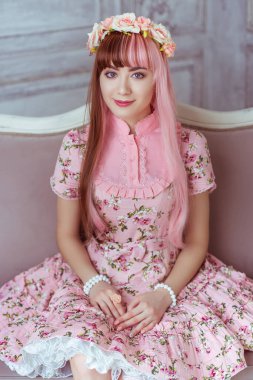 Pembe elbiseli güzel bir kadın, parlak bir odada, kanepede oturuyor, Lolita. Japon sokak modası.