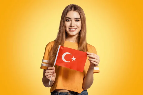 A beautiful young woman holds in her hands the flag of Turkey. Exchange student learning a foreign language. Tourist traveling. Turkish bride. Football fan.