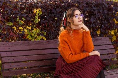 Ekim ayında güzel, genç bir kadın sonbaharda bir bankta oturur. Kız yuvarlak giyinmiş, cam gözlüklerle. Öğrenci öğretmen dinleniyor, parkta yürüyor..