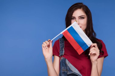Mavi arka planda Rusya Federasyonu bayrağı taşıyan güzel bir esmer kadın. Rusça öğrenme.