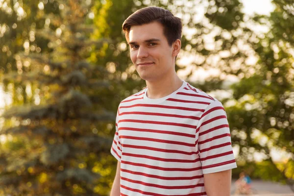 Portrait of a handsome, young man in a park. on the background of greenery. Life style, copy space.