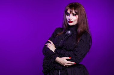 Cadı, mor arka planda siyah gotik elbiseli bir vampir..