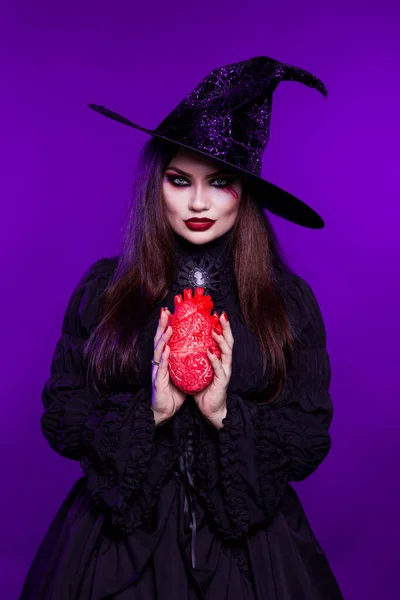 Hermosa Mujer Una Bruja Con Sombrero Sostiene Corazón Sobre Fondo —  Fotos de Stock