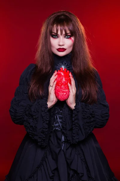 Hermosa Mujer Una Bruja Vampiro Sostiene Corazón Sobre Fondo Rojo —  Fotos de Stock