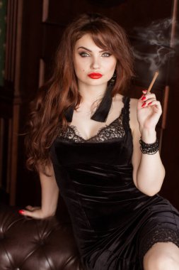 Siyah elbiseli güzel seksi bir kadın sigara içiyor ve viski içiyor. Koltuk göğüs tarlası. Hanımım, Casus Kız