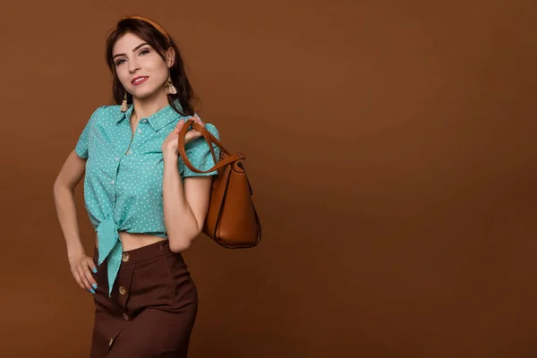 革のハンドバッグとエレガントなファッショナブルな女性 茶色のバッグを持つスタイリッシュなピンアップの女の子 女性ファッション流行 ブラウン コーヒーの背景 スペースのコピー — ストック写真