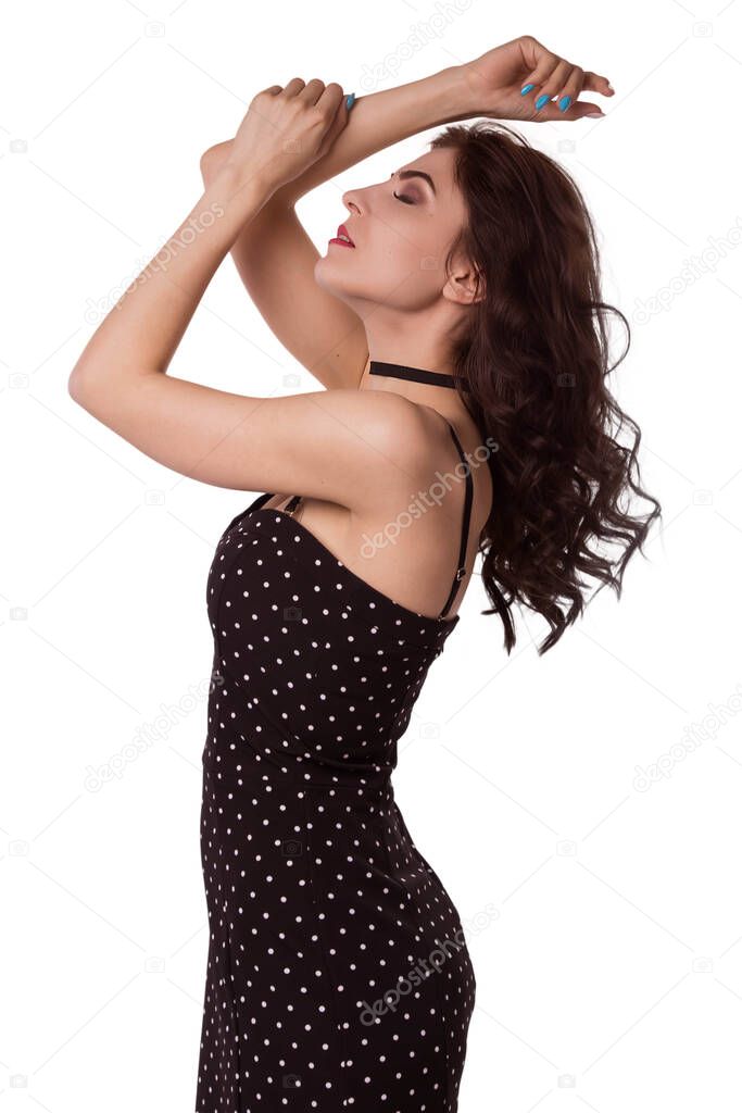 A beautiful, caucasian brunette woman in a black tight dress is standing in a sexy pose. Flirt, pose.