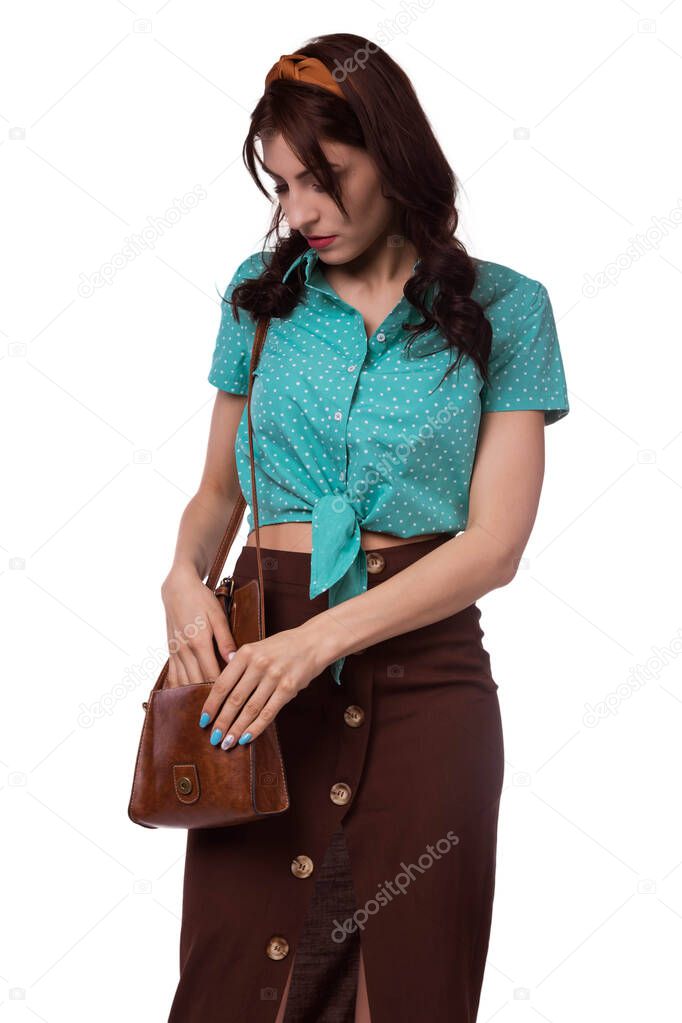 A beautiful, Caucasian brunette woman, on a white background, wearing a brown skirt and a blue blouse pulls out money from a bag. Tourist, sexy housewife. Safety at rest.