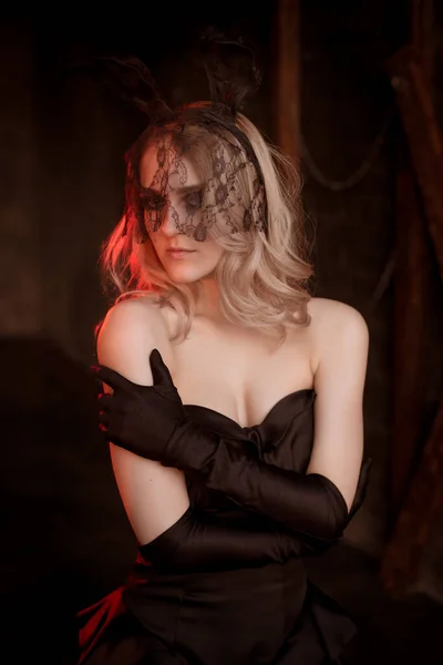 一个穿着黑色晚礼服 戴着长长的手套 戴着花边耳朵的美丽性感的年轻女人 眼睛上的面纱党的形象 — 图库照片