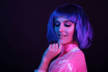 Neon light stüdyo yakın plan, peruklu mutlu kadın modelin portresi. Gece hayatı, gece kulübünde parti. Boşluğu kopyala.