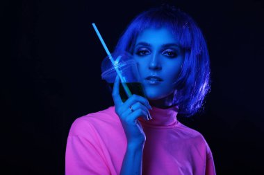 Neon light stüdyo yakın plan mutlu kadın modelin plastik bardak ve kokteyl içeren portresi. Gece hayatı, gece kulübünde parti. Boşluğu kopyala.