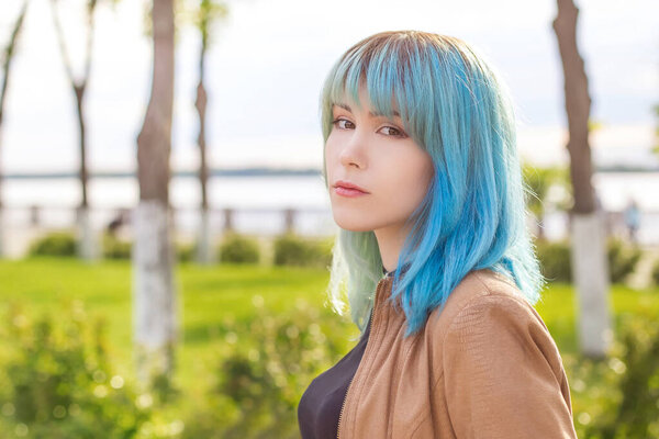 Close-up portrait of a young beautiful woman, female students in a park with colored, blue hair.