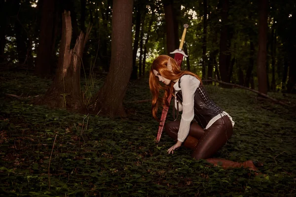 Fantasy is a woman elf, magician, warrior with sharp ears, with orange hair and a leather corset and with a sword. She was wounded, fell, tired, kneeling. Defeated in battle. Cosplay.