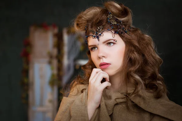 Medieval outfit of a princess, a sorceress, a witch with a tiara on her head. Portrait of a beautiful teenage girl, women. Serious, pensive look. Fairy-tale costume.