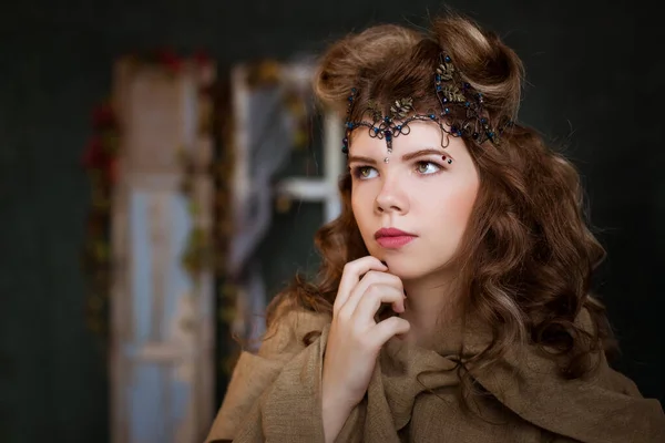 Medieval outfit of a princess, a sorceress, a witch with a tiara on her head. Portrait of a beautiful teenage girl, women. Serious, pensive look. Fairy-tale costume.