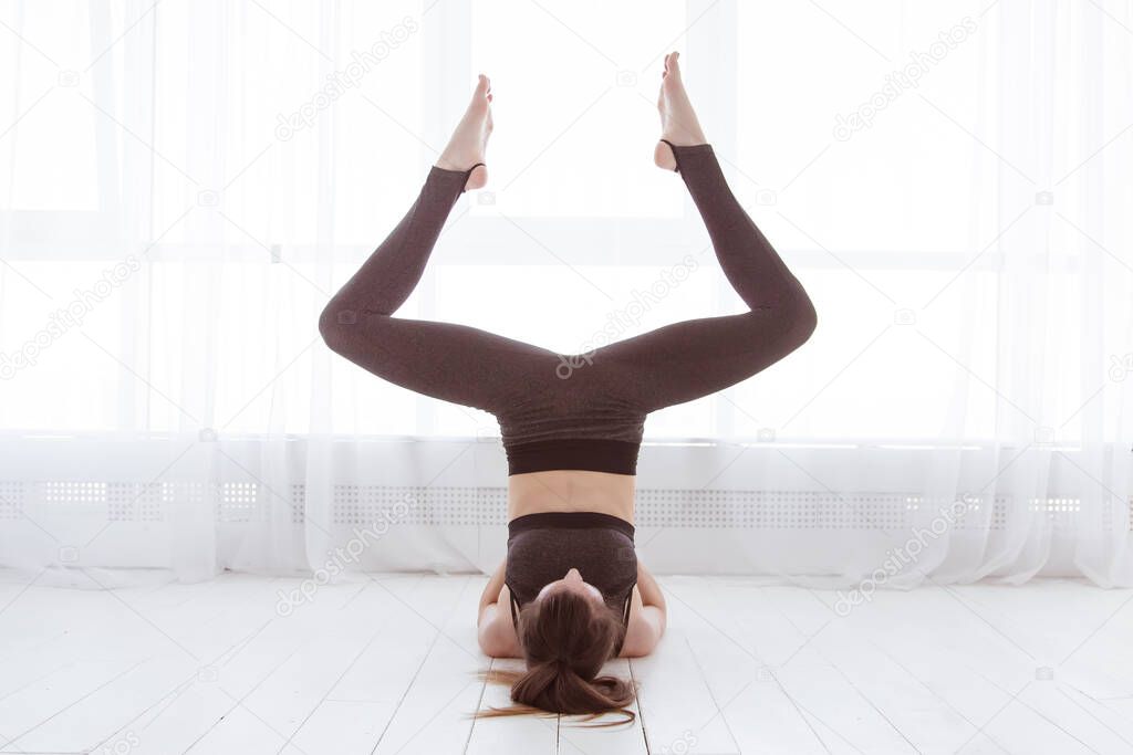 Fitness, stretching workout, attractive mature woman in sportswear working out in sports club, keeping fit, doing shoulderstand exercise, Viparita Karani, Upside-Down Seal pose in class. Lifestyle.