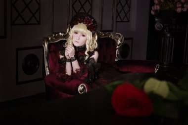 Güzel, küçük, sarışın bir kız kırmızı, gür, eski bir elbiseyle pahalı bir koltukta oturuyor. Kadın, vampir Claudia. Bir prenses. Japon usulü lolita, güzel kostüm. Sokak modası.