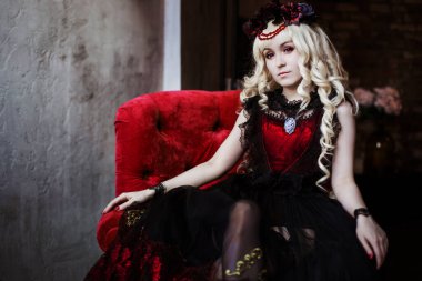 Gotik elbiseli ve kırmızı sandalyede oturan mor gözlü güzel bir kadın prenses. Peri masalı, hayal..