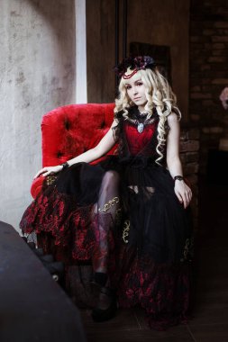 Gotik elbiseli ve kırmızı sandalyede oturan mor gözlü güzel bir kadın prenses. Peri masalı, hayal..