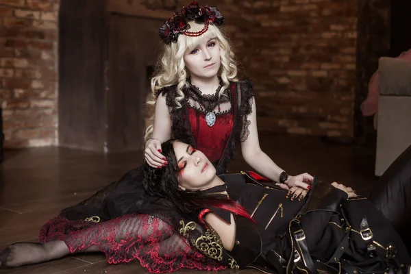 Demon, a vampire lies on the lap of a beautiful princess woman. Gothic costume. Visual kei, aristocrat. Fairy tale, fantasy.