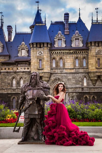 Красивая Женщина Королева Бордовом Роскошном Платье Стоит Скульптуры Рыцаря Викинга — стоковое фото