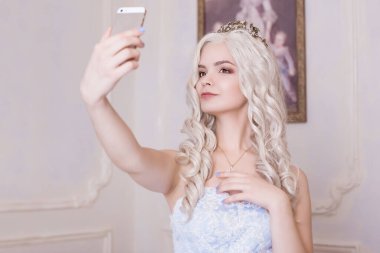 Çekici bir kız, taç giymiş sarışın bir kadın, özçekim yapıyor. Şımarık bir kız, bir oligarşinin kızı. Pahalı bir telefondaki fotoğraf, narsist. Resmin arka planındaki prenses..
