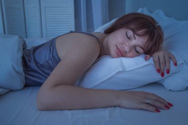 Yatak odasında güzel bir kız, yatakta yatıyor. Beyaz çarşaf. İyi geceler..