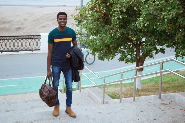 Черный Молодой Человек Спускается Лестнице Городе Держа Руках Сумку Пальто — стоковое фото