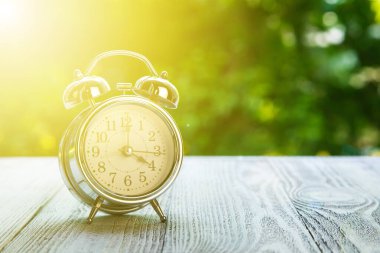 Montaj ürünü gösterimi ya da tasarım anahtarı için yeşil soyut arkaplan bulanık ahşap masa üstü. Saat 16: 00 'da yeşil bahçe saatinde ahşap masada.