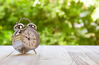 Montaj ürünü gösterimi ya da tasarım anahtarı için yeşil soyut arkaplan bulanık ahşap masa üstü. Saat 10 'da yeşil bahçe saatinde ahşap masadaki saat.