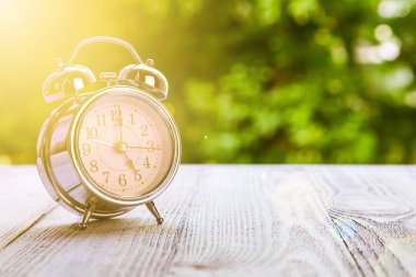 Montaj ürünü gösterimi ya da tasarım anahtarı için yeşil soyut arkaplan bulanık ahşap masa üstü. Saat 17: 00 'de yeşil bahçe saatinde ahşap masada..