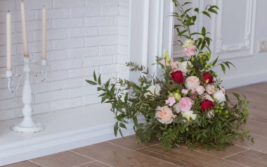 Çiçek aranjmanı ve mumlarıyla beyaz dekoratif şömine.