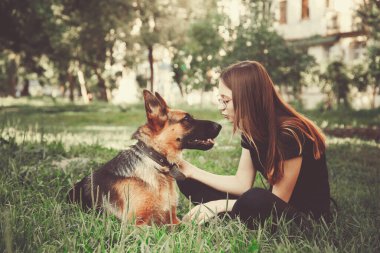 Parkta Alman çoban köpeği olan bir kadın. Retro tonlama.