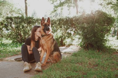 Parkta Alman çoban köpeği olan bir kadın. Retro tonlama.