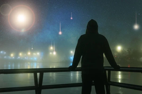 Zakapturzona sylwetka walcząca z obcymi, Ufo, światłami statku kosmicznego nad rzeką. W tajemniczą mgłę, zimową noc, ze wszechświatem gwiazd. Koncepcja science fiction. — Zdjęcie stockowe