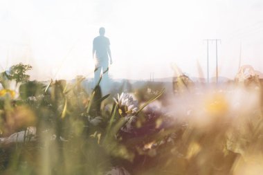 Bir tarlada siluetli bir insanla yakın çekim yapmak için çift çekim. Gün batımına karşı deneysel, kurgu gibi soyut bir rüyayla