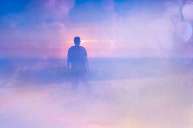 Tepenin tepesinden gün batımına bakan bir adamın çift pozu. Kurgu gibi soyut ve deneysel bir rüyayla.