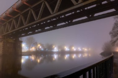 Kasvetli, atmosferik sisli bir kış gecesinde nehrin üzerinden geçen Viktorya Çelik Demiryolu Köprüsü. Worcester, River Seven, Uk