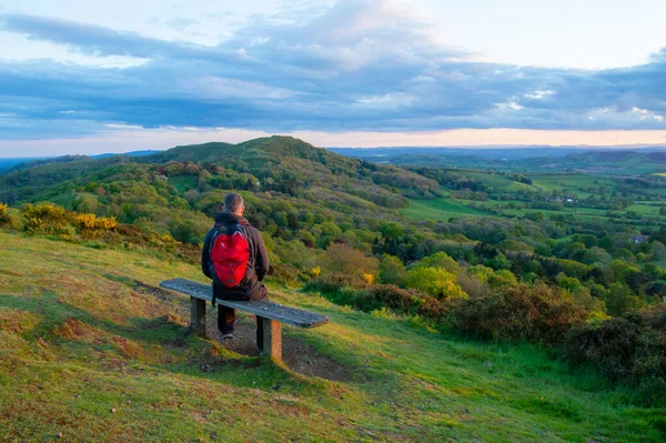 春天的一天 一个徒步旅行者坐在长椅上 眺望着外面的英国乡村 Malvern Hills — 图库照片