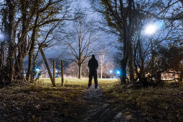 Postava Kápi Rýsující Proti Pouličnímu Světlu Kraji Města Noci — Stock fotografie