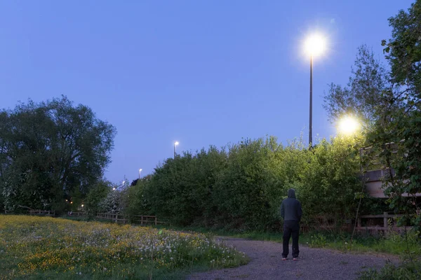 Gizemli Kukuletalı Bir Adam Sokak Lambasına Bakıyor Bir Bahar Akşamında — Stok fotoğraf